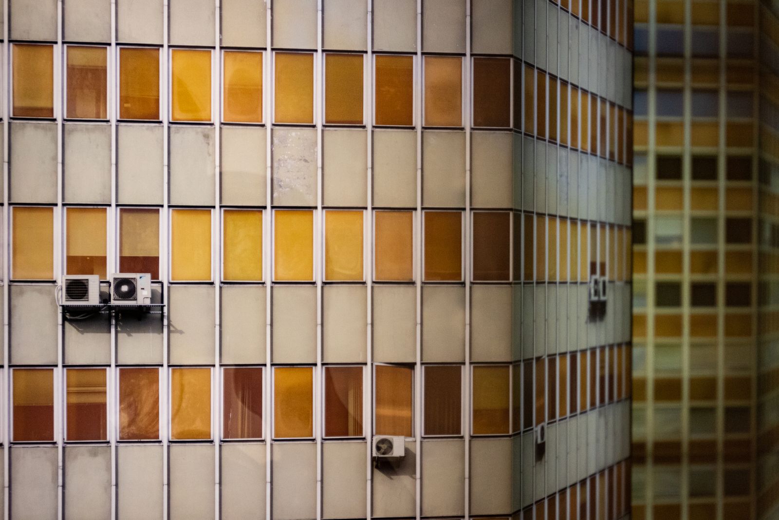 Outdoor air-conditioning units mounted beside a multistory residential building
