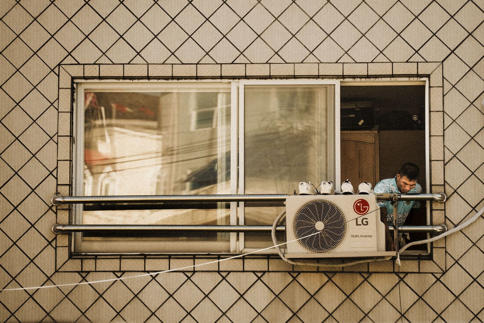 An outdoor air-conditioning unit beside a building while a technician works nearby