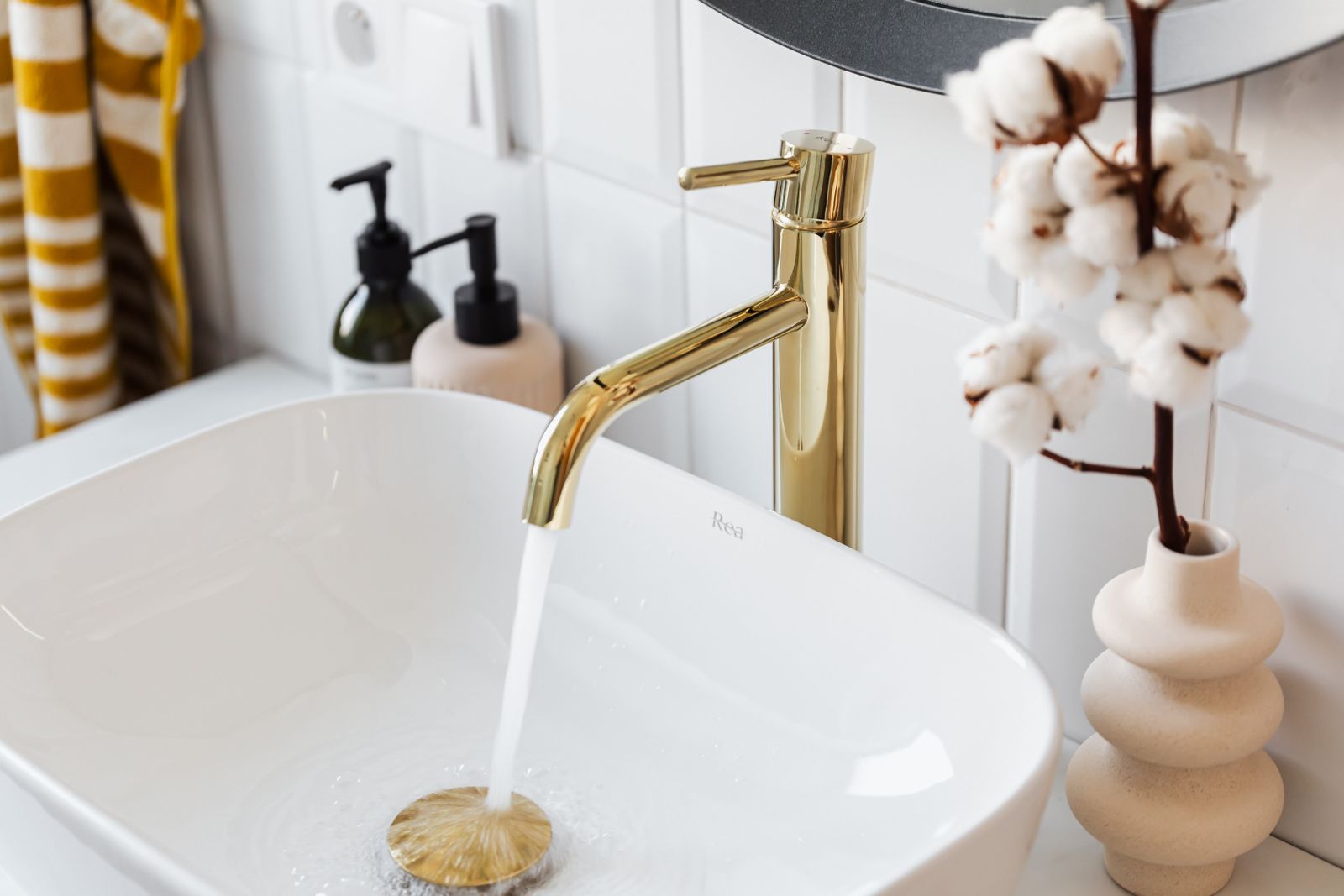 A polished brass faucet above a white residential bathroom basin