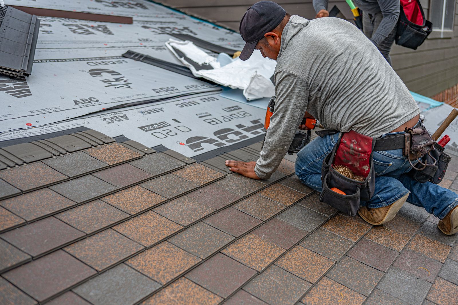 A roofer placing shingles as part of a complete roof installation