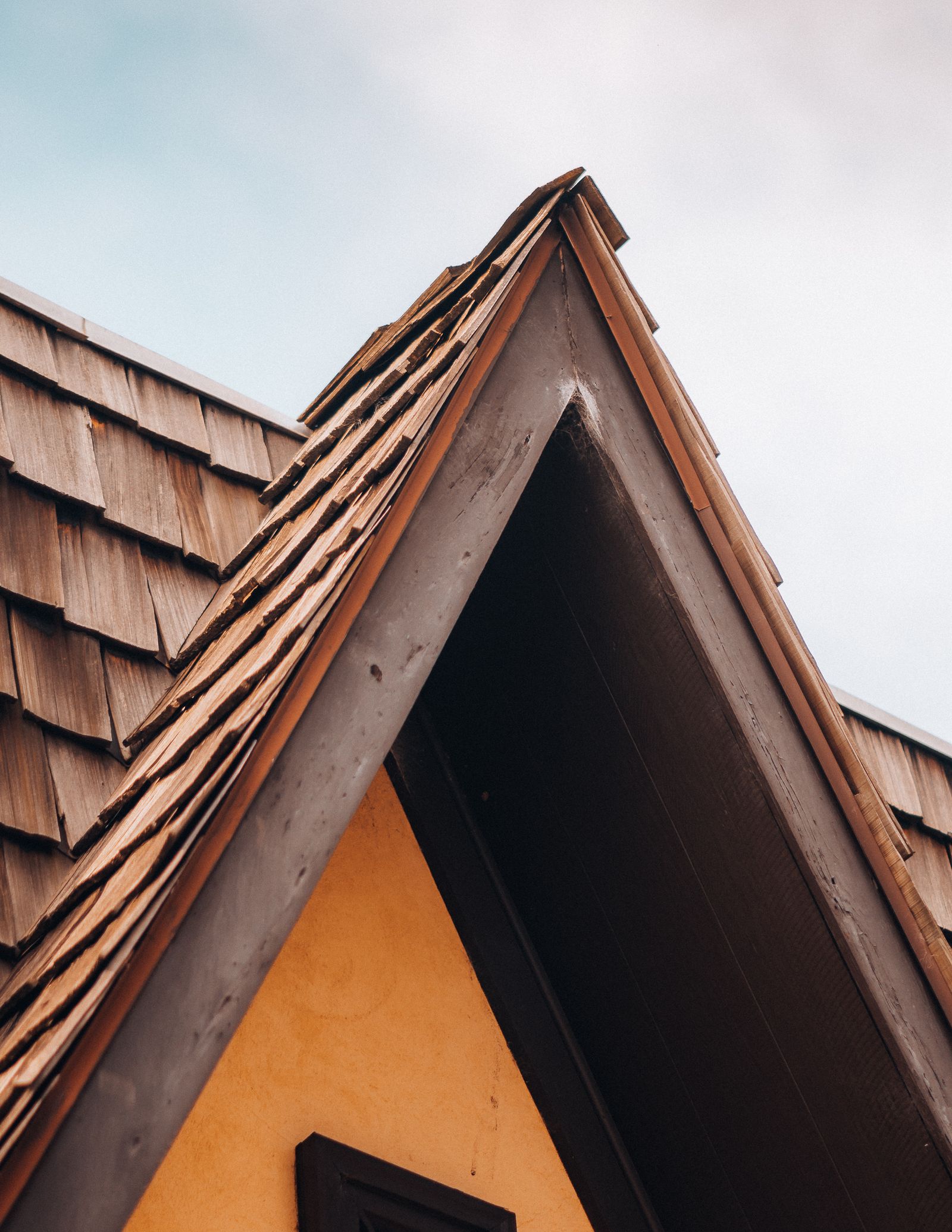 A steep roofline with natural wood-shingle covering and finished edge details
